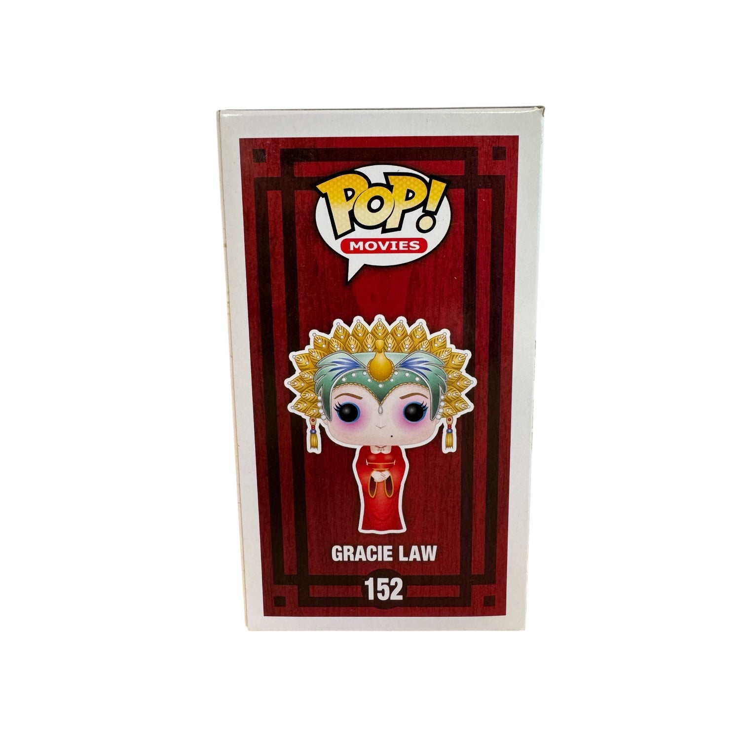 Woman wearing red dress, green and hold head piece and blue and pink eye make up.