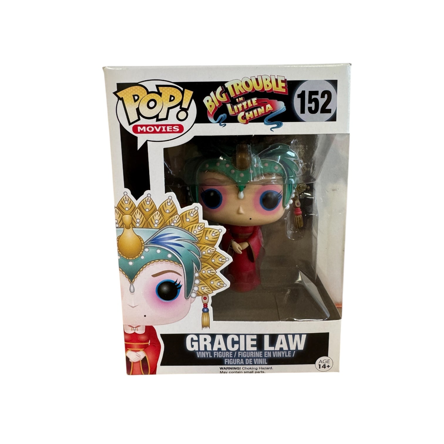 Woman wearing red dress, green and hold head piece and blue and pink eye make up.