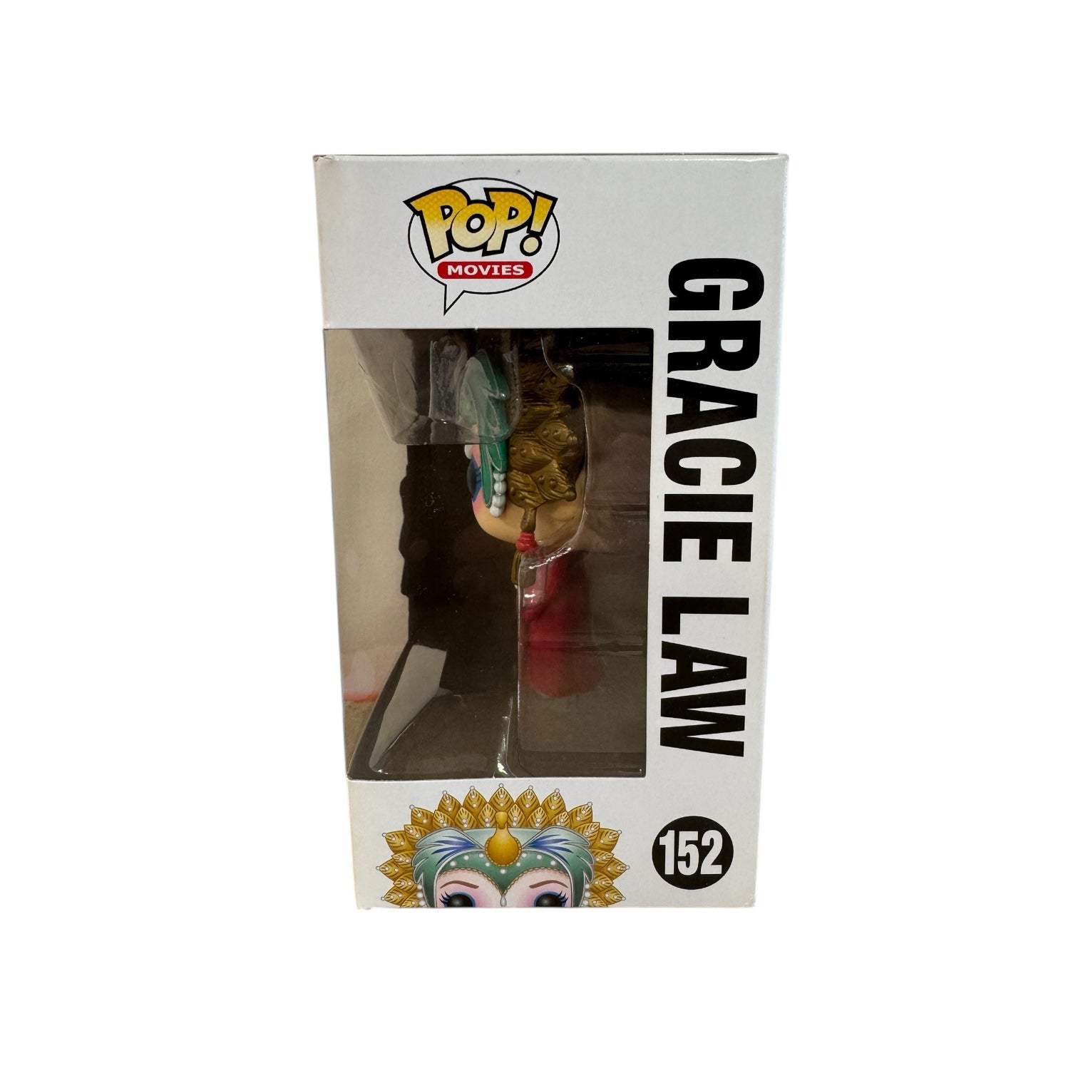 Woman wearing red dress, green and hold head piece and blue and pink eye make up. 